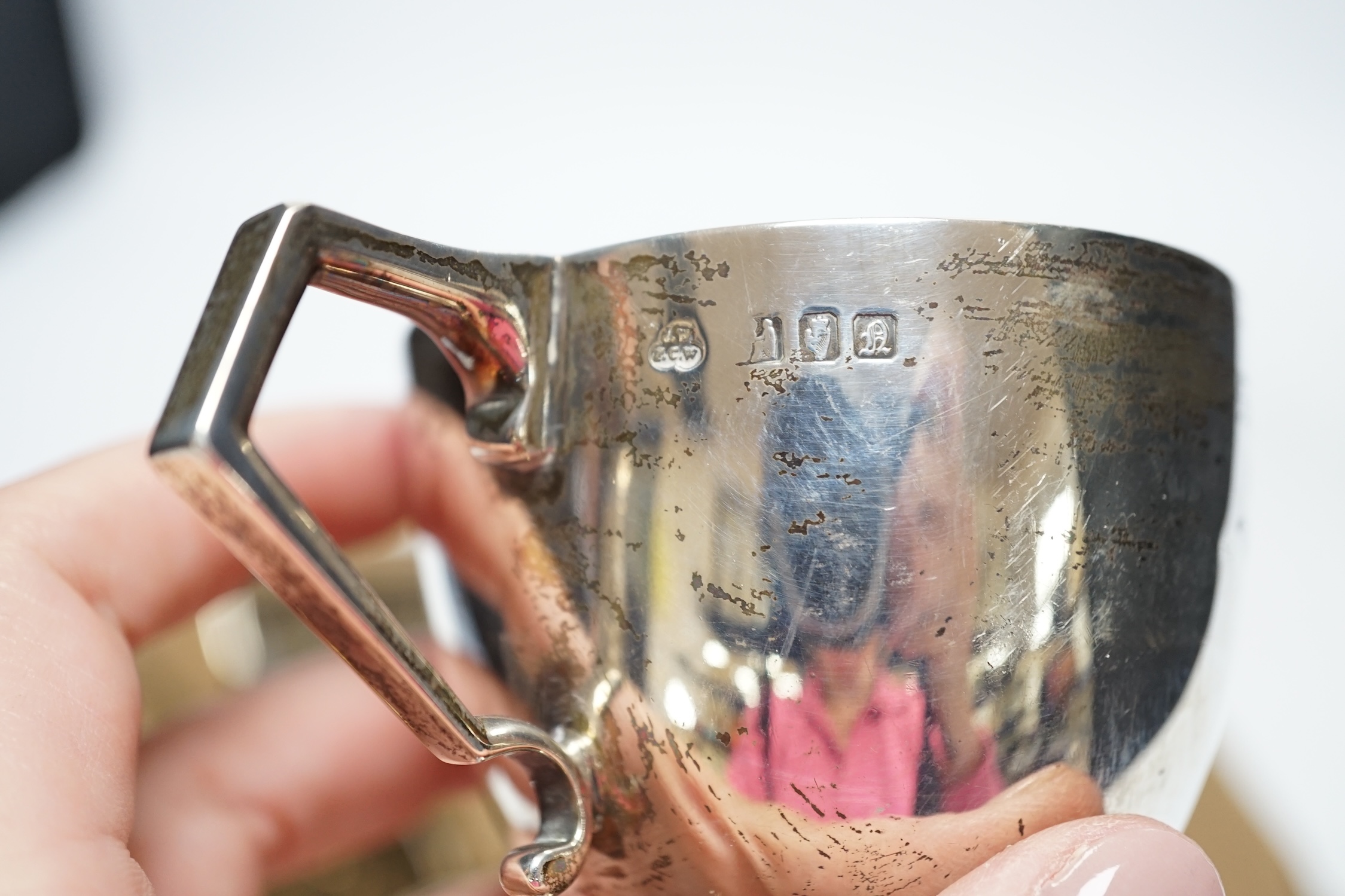 Two early 20th century demi-fluted silver cream jugs and a similar sugar bowl, an Irish silver tea cup and an Indian? white metal mug, gross weight 16.7oz. Fair condition.